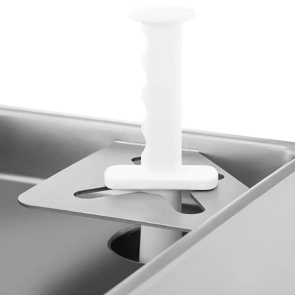 Industriell kjøttkvern, nærbilde av hvitt plastverktøy gjennom metallplate, sett ovenfra med kjøkkenredskap synlig.