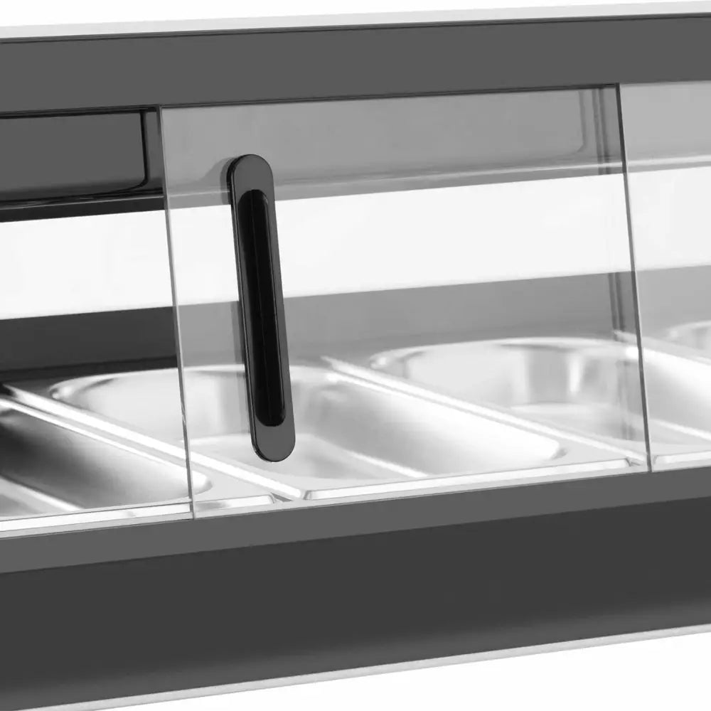 Innredning overkjølingsdisk, nærbilde av sort håndtak på glassdør med stålkantede beholdere bak glasset.