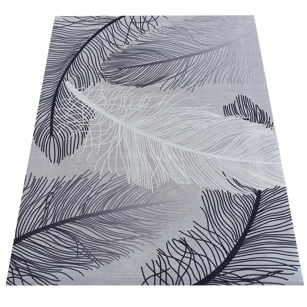 Interiør Tepen grått teppe 160 x 220 cm, sett ovenfra med grafisk fjærmønster i svart, grått og hvitt.
