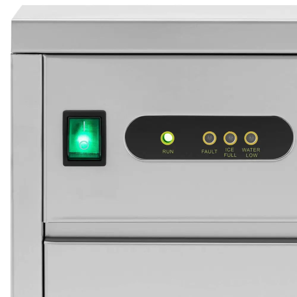 Ismaskin, nærbilde av kontrollpanel med grønn av/på-bryter og statuslys for drift og nivåvarsling.