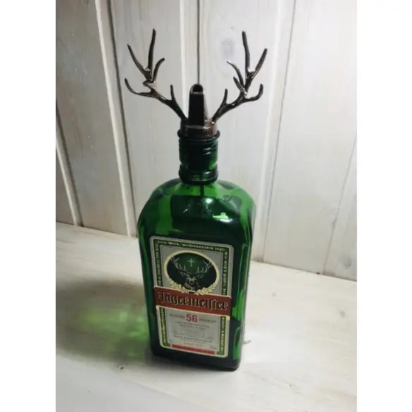 Jägermeister tappeapparat med grønn flaske og metallgevir-helletut foran lyst trepanel.