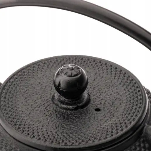 Jernkanne for te Jang, nærbilde ovenfra med strukturert lokk, dekorativ knott og delvis synlig hank.