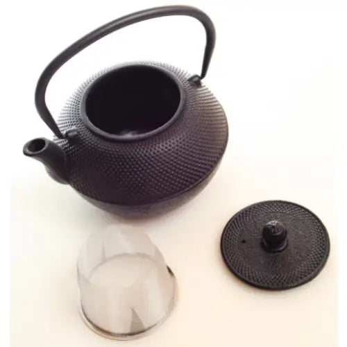 Jernkanne og sil for te, sett ovenfra med synlig strukturert overflate, lokk og buet hank.