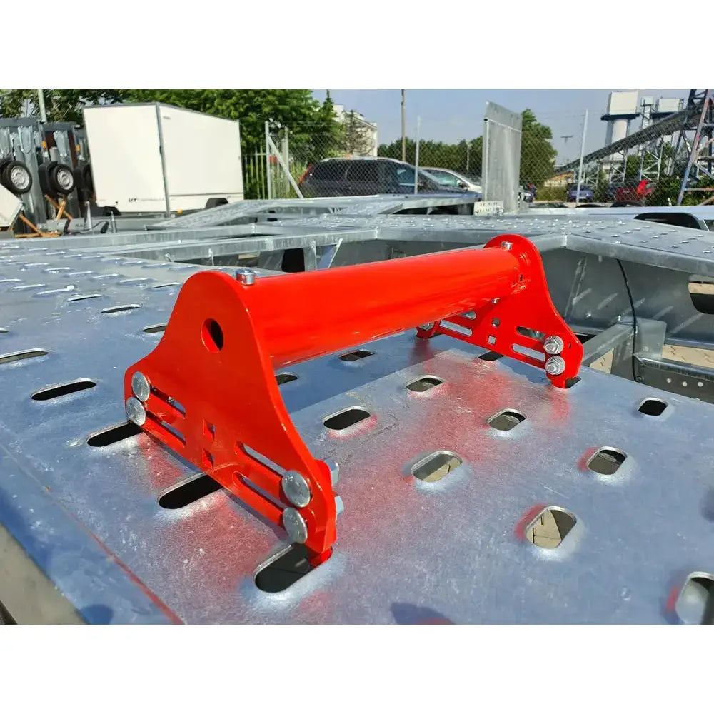 Justerbar hjulblokk i rød metall, skrå utendørsvisning med festebolter og justerbare spor på sidene.