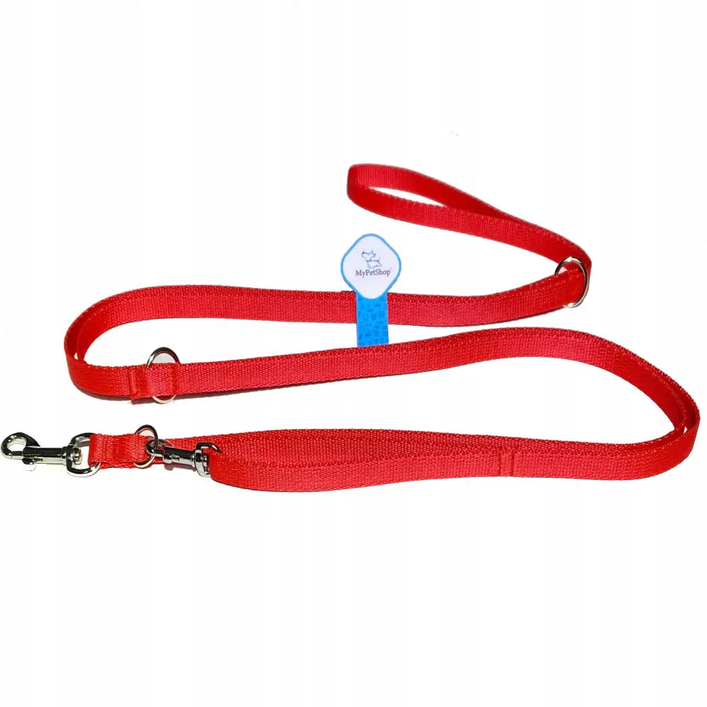Justerveskbart rødt hundekobbel i nylon med sølvkroker og blå etikett, fotografert ovenfra mot hvit bakgrunn.