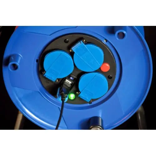 Kabeltrommel med tre blå stikkontakter sett ovenfra, én kontakt i bruk og grønn indikatorlampe tent.