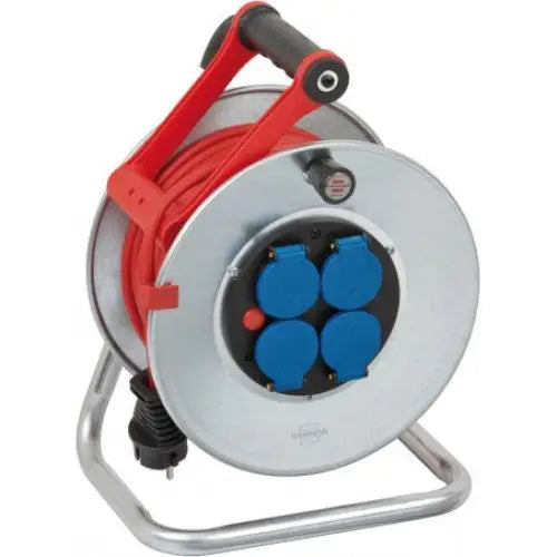 Kabeltrommel Garant S, metallhus med rødt håndtak og fire blå stikkontakter, sett skrått på stativ.