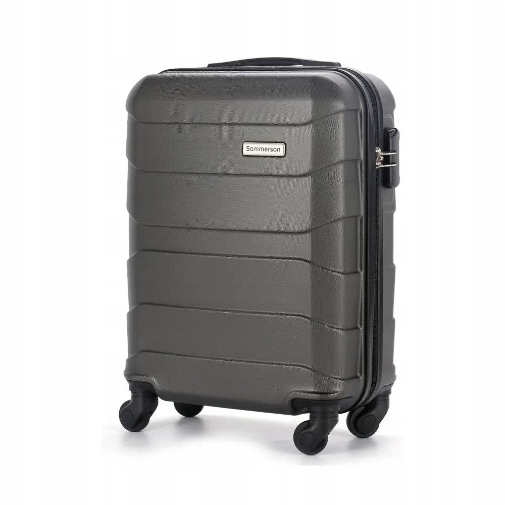 Kabinveske håndbagasje i mørk grå plast, skrå vinkel med fire svingbare hjul og topphåndtak.