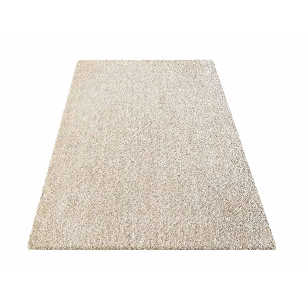 Kamel teppe i lys beige, skrått fotografert for å vise mykt, tett materiale og rektangulær form.