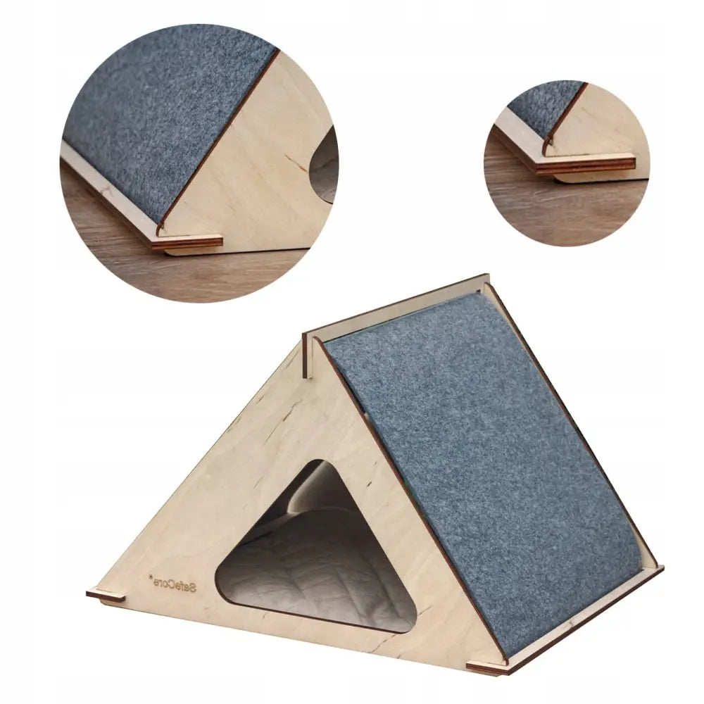 Katteseng Safecore Hytte 2, trekantet lyst trehus med grå filt og tydelig trekantet inngang, sett fra skrå vinkel.