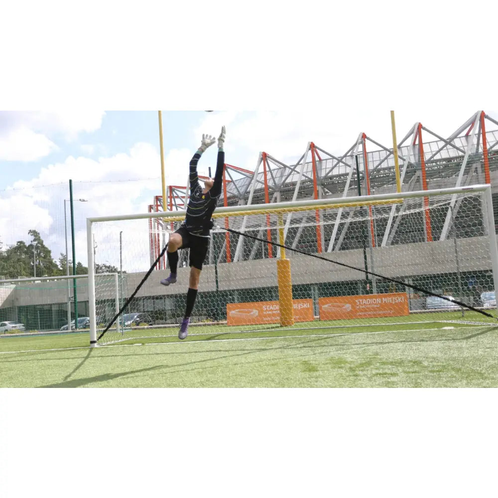 Keeper Treningkummi, fotballkeeper hopper mot mål med elastisk treningsline rundt livet på gressbane.