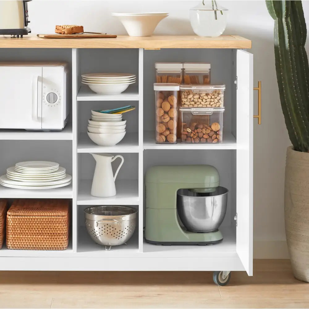 Kjøkkenøy med hylle, hvit skjenk på hjul med treplate, servise og grønn kjøkkenmaskin nederst til høyre.
