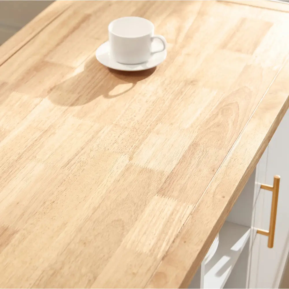 Kjøkkenøy med lyst treunderstell, sett ovenfra med hvit kopp, asjett og gulldetalj på håndtak.