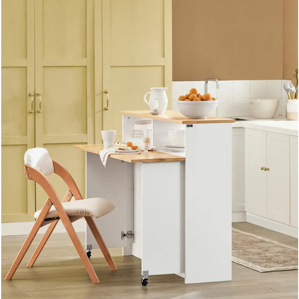 Kjøkkenøy med skap og sammenleggbar barstol, hvit base, lys treplate, dekket frokost og synlig servise.