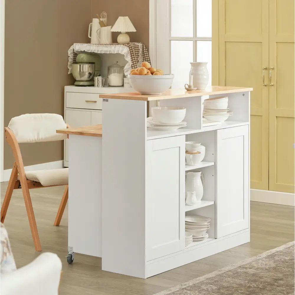 Kjøkkenøy med skap og sammenleggbar barstol, skråvisning med åpne hyller fylt med servise og keramikk.