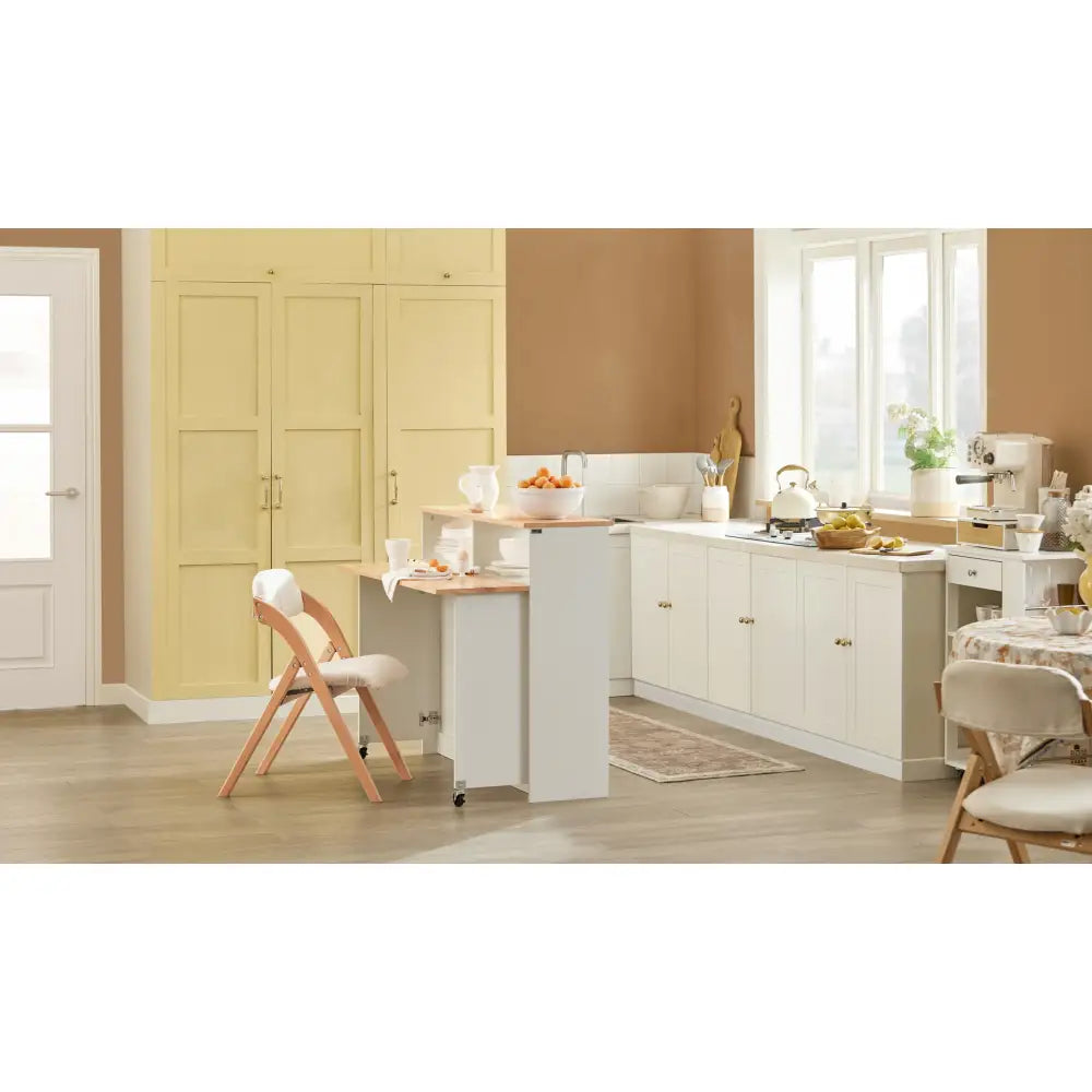 Kjøkkenøy med skap og sammenleggbar barstol, plassert i lyst kjøkken med beige skap og store vinduer.