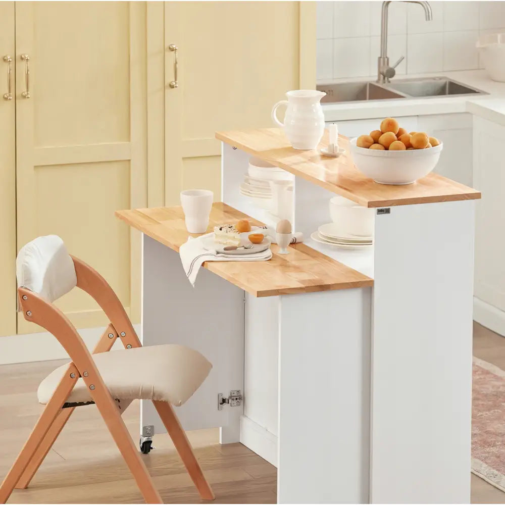 Kjøkkenøy med skap og sammenleggbar barstol, sidevisning med beige polstret sete mot lys treplate.