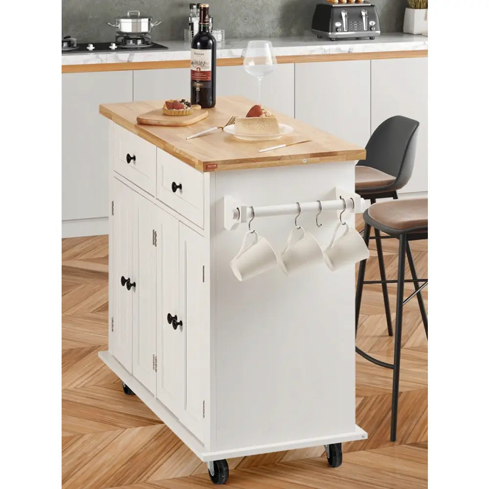 Kjøkkenøy på hjul med hvit base, lys treplate og svarte knotter, sett skrått med tre kopper hengende på siden.