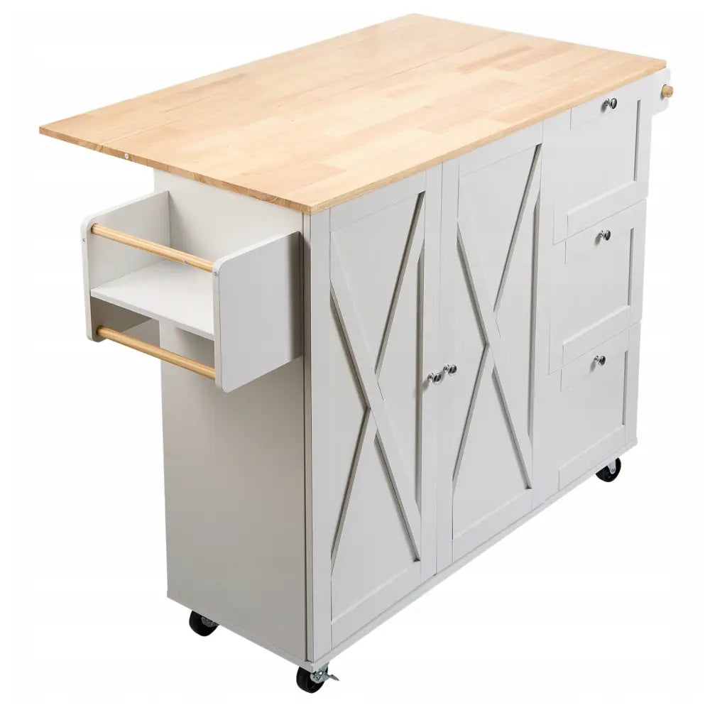 Kjøkkenøy på hjul i hvitt, skråvisning som fremhever kryssdekor, tre skuffer og sidehylle med trehåndtak.