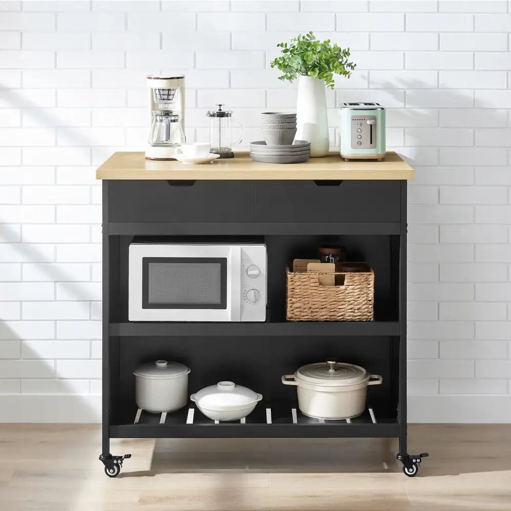 Kjøkkenøy på hjul i sort og eik, frontvisning med åpne hyller fylt med servise, gryter og mikrobølgeovn.