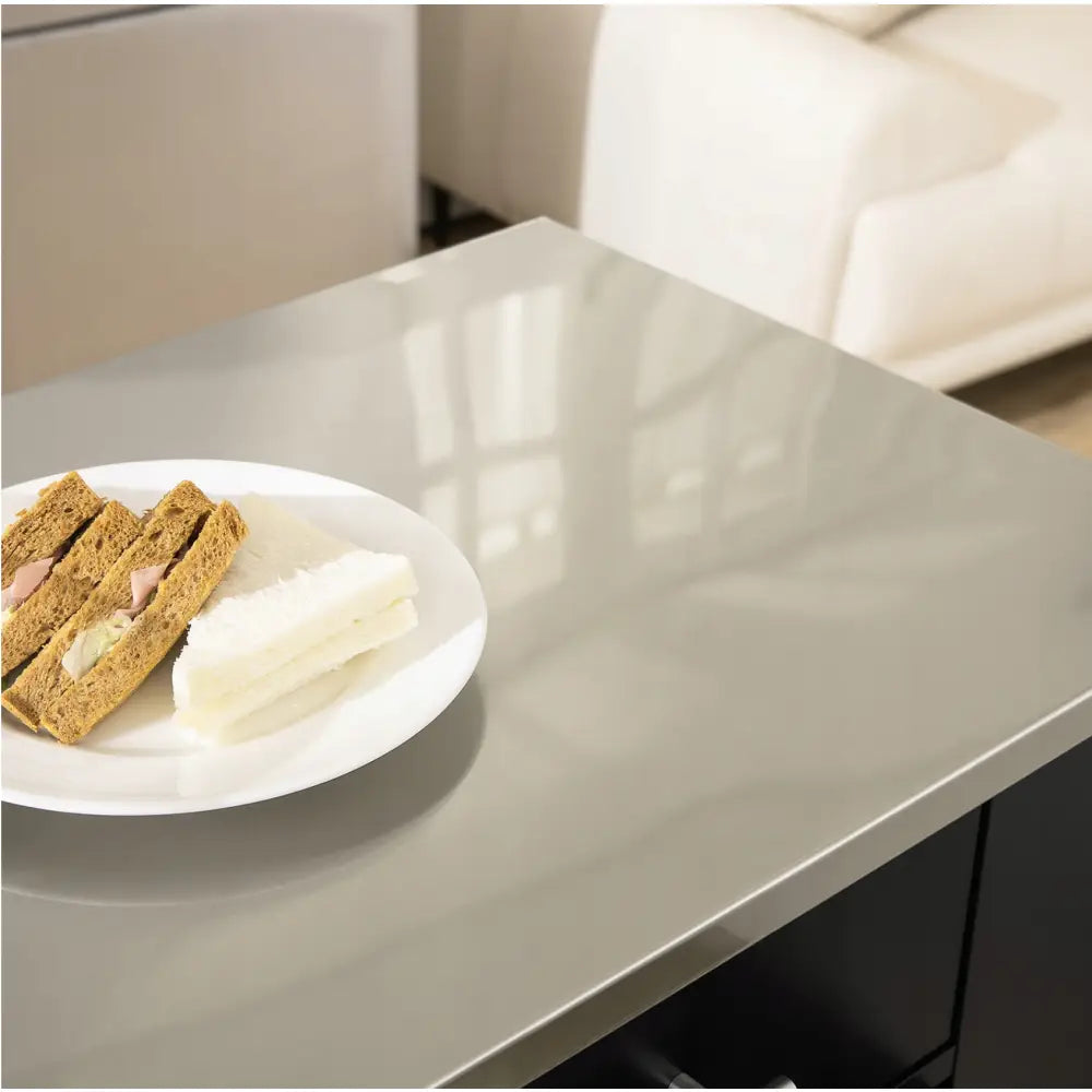Kjøkkenøy skjenk med grå høyglans bordplate, hvitt fat med sandwicher plassert i hjørnet.