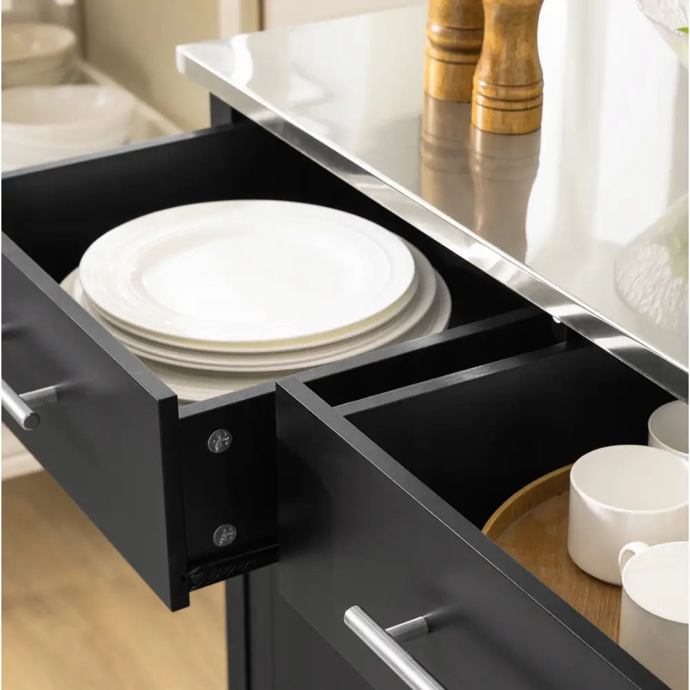 Kjøkkenøy med to åpne, svarte skuffer sett ovenfra, viser oppbevaring av hvite tallerkener og krus.