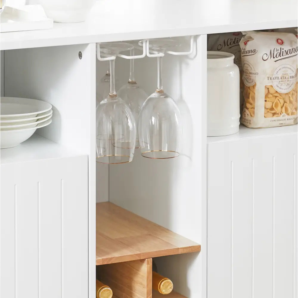 Kjøkkenøy med hvit hylle, hengende vinglass, trefarget vinhylle og synlige tallerkener og pastabokser.