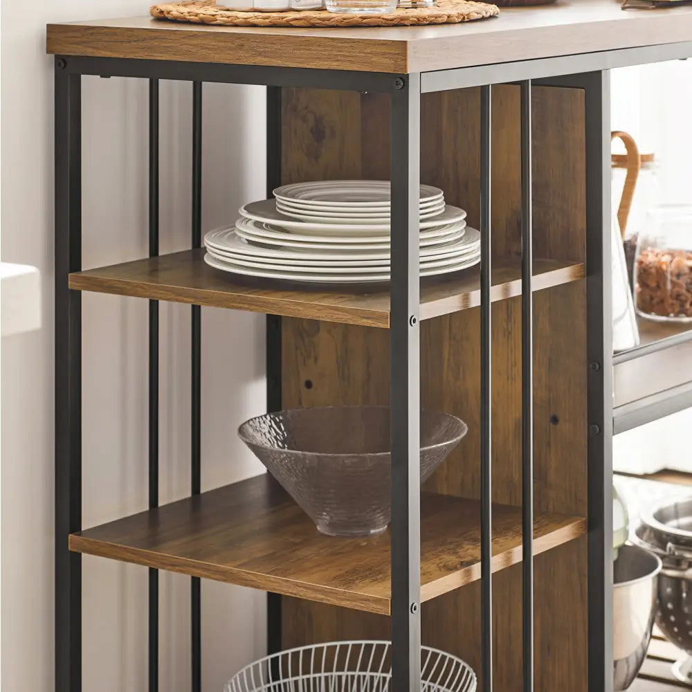Kjøkkentrolley i sort metall og tre, sidevisning med hyller fylt av tallerkener, glassbolle og metallkurv.