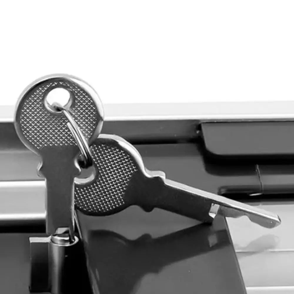 Nærbilde av to sølvfargede nøkler til kjøleboks med glasslokk, liggende på mørk blank overflate.