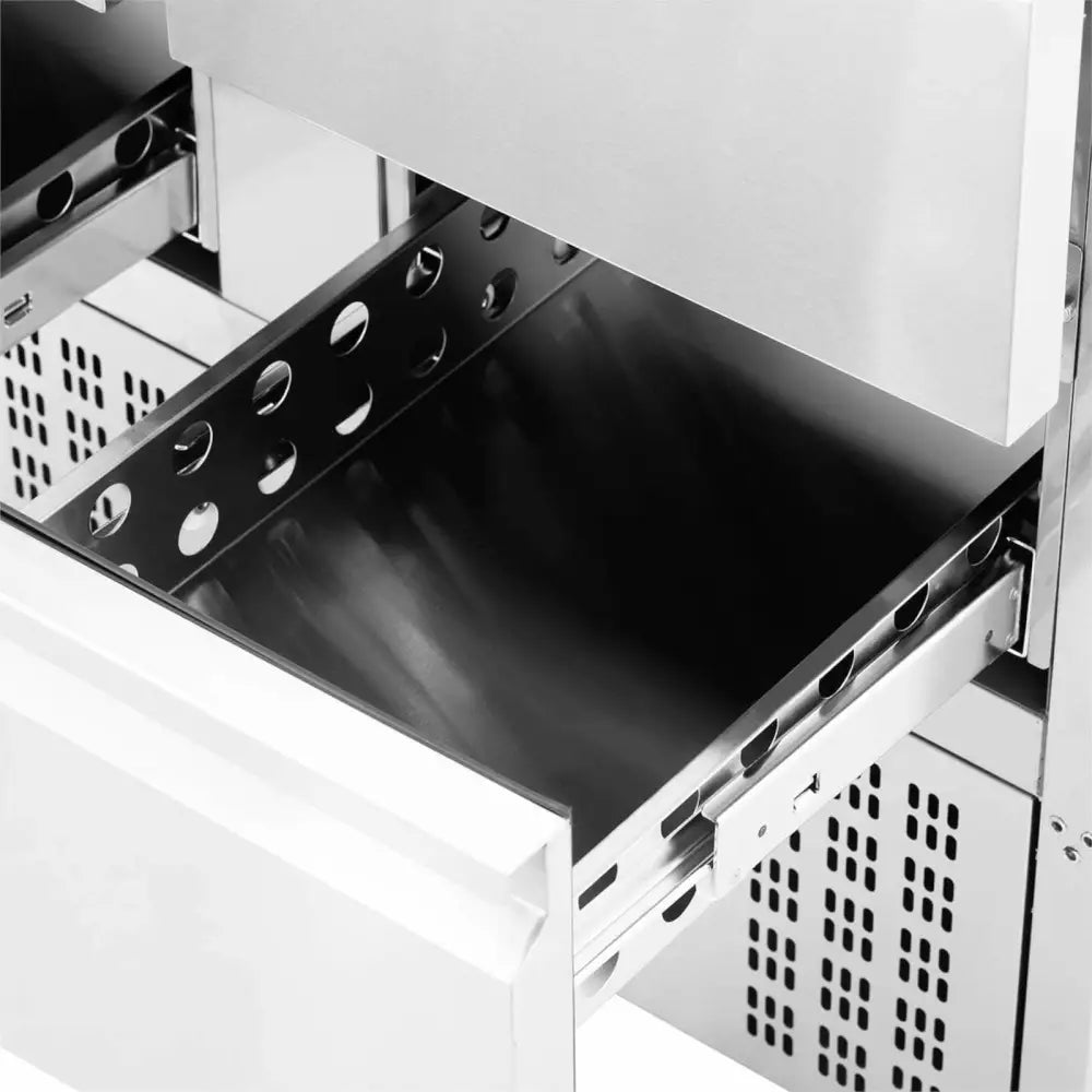 Kjølebord med fire skuffer, skrå vinkel som viser åpen skuff med perforerte metallkanter og robust stål.