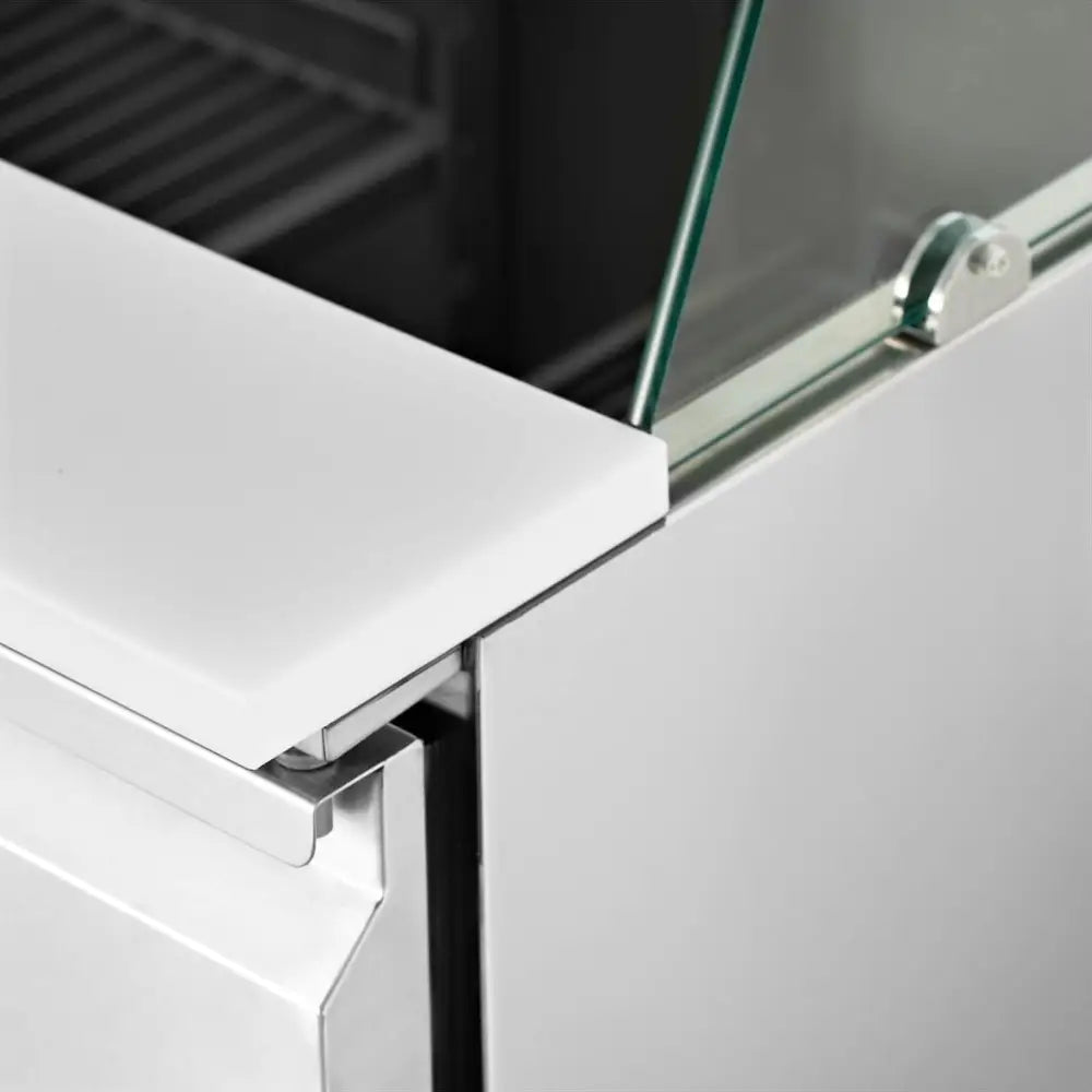 Kjøleromsalatbord med glassvindu, detalj av hjørne med rustfritt stål og metallfeste mot hvit topp.