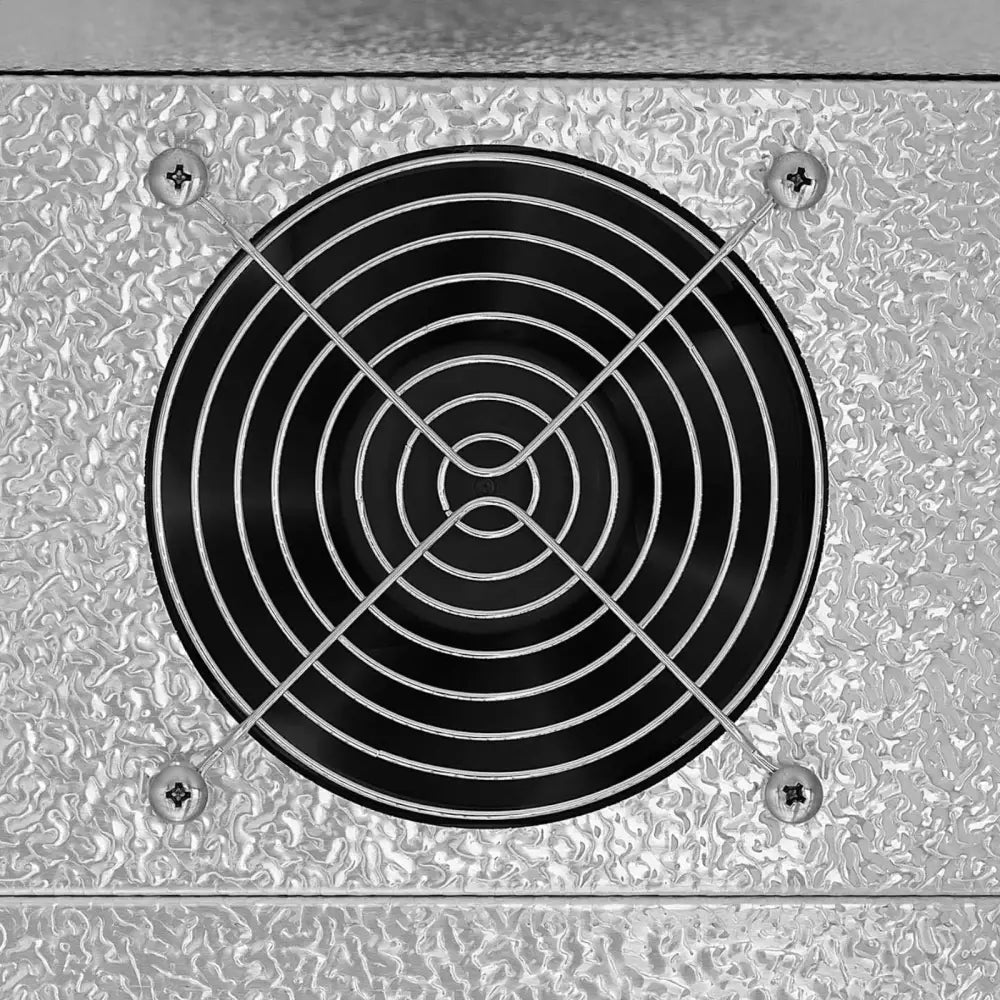 Kjøleskap Bar Kjøler, detalj av sort ventilasjonsvifte med metallgitter på sølvfarget bølget overflate.