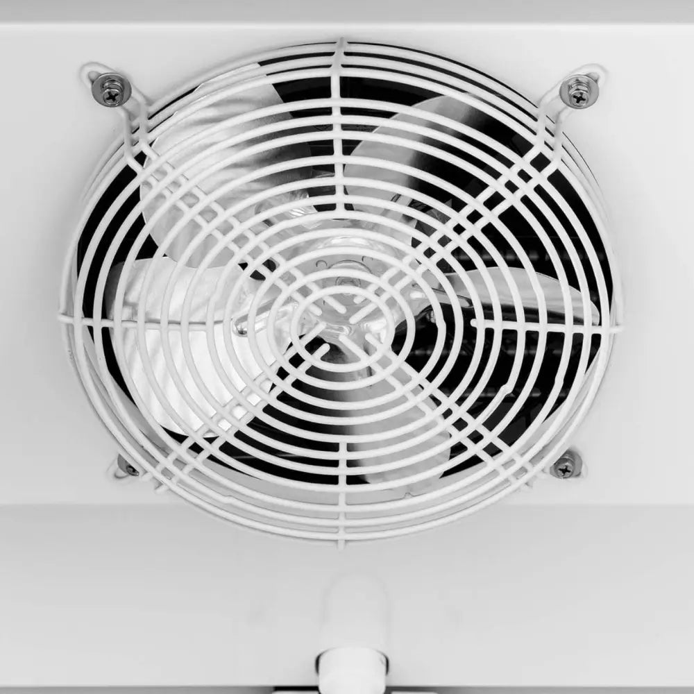 Metallvifte med fire blanke blader og beskyttelsesgitter, montert i kjøleskapets innside.