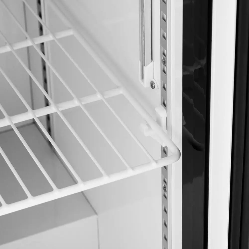 Hvit metallhylle med gittermønster, sett fra siden, viser justerbare høydeposisjoner inne i kjøleskapet.