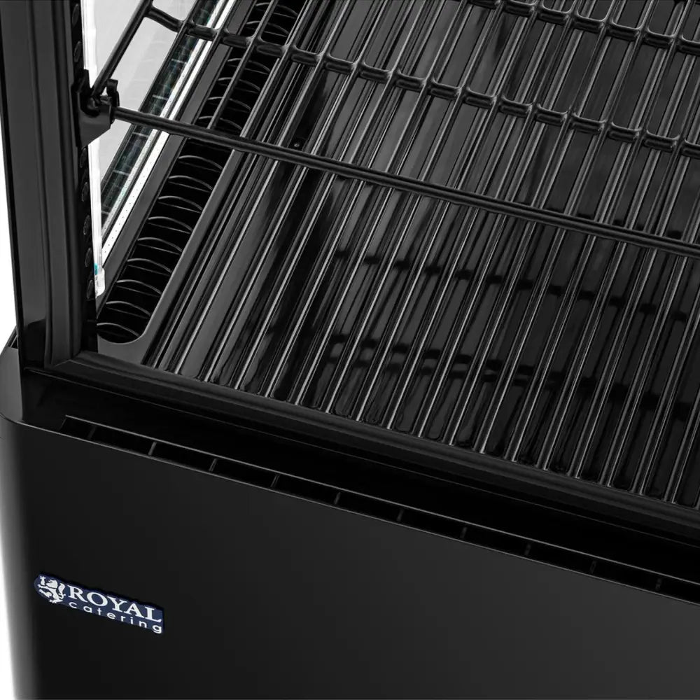 Kjølethevet utstillingsdisk i svart, skrå oversiktsvisning av metallrist og glasslokk med Royal Catering-logo.