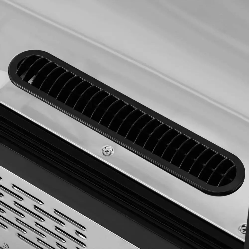 Kjølethylle med glassfront, detaljert nærbilde av svart luftventil med gitter og børstet stålkant.