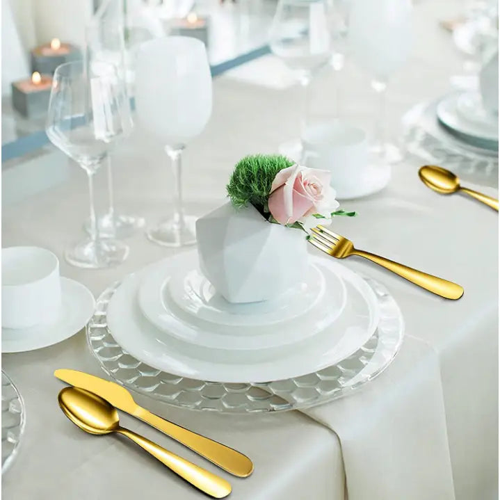 Klassisk bestikksett i gull, elegant dandert for seks personer på hvitt servise med blomster og vinglass.