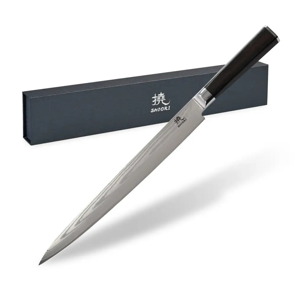 Kokkekniv i japansk damaskstål med blankt blad og mørkt håndtak foran elegant gaveeske.