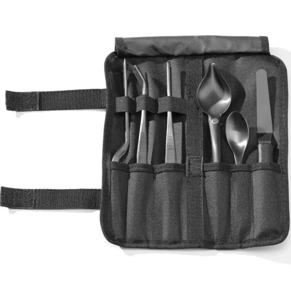 Kokkekunst Toolsett for Matdekorering, sort tekstiletu sett ovenfra med pinsetter, skjeer og spatel i lommer.