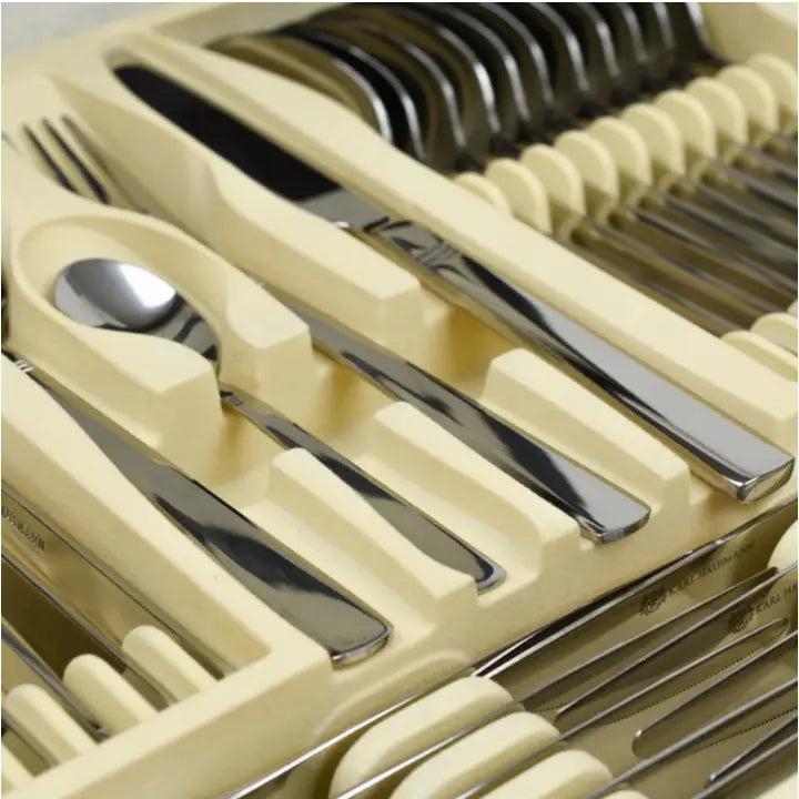 Komplett bestikksett med 72 blanke deler sortert i beige oppbevaringskoffert, skrått nærbilde av kniver, gafler og skjeer.