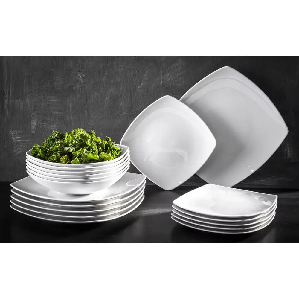 Komplett porselen middagsservise, stablede firkantede tallerkener og skåler, én skål med grønn salat.