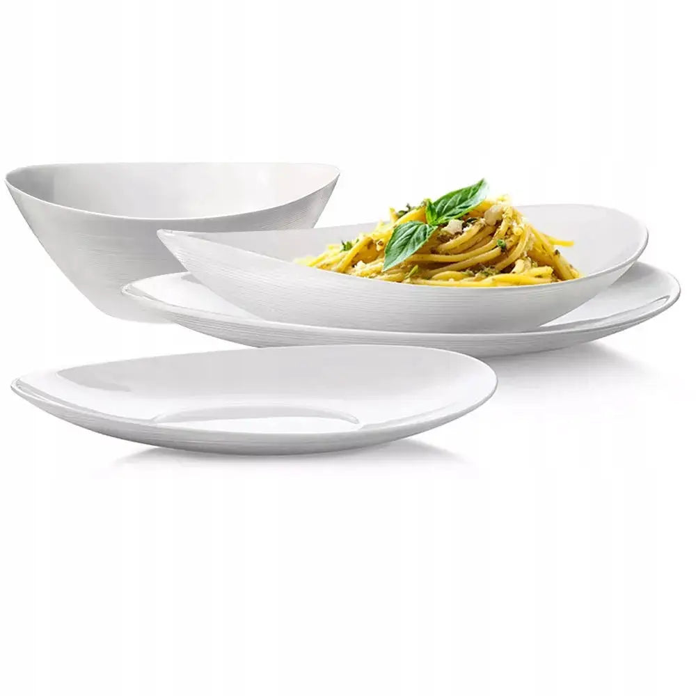 Komplett servise sett med fire hvite porselenstallerkener, én servert med pasta og urter, skrå vinkel.