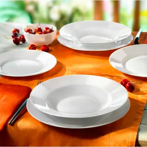 Komplett servise Toledo, hvite porselenstallerkener og suppetallerkener sett ovenfra på oransje duk med kirsebær.