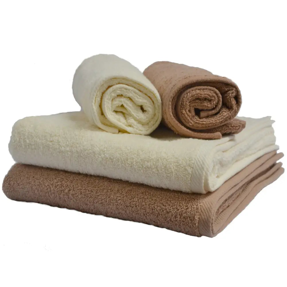 Komplett toalettsett med fire beige og hvite bomullshåndklær, to rullet og to brettet, sett fra siden.