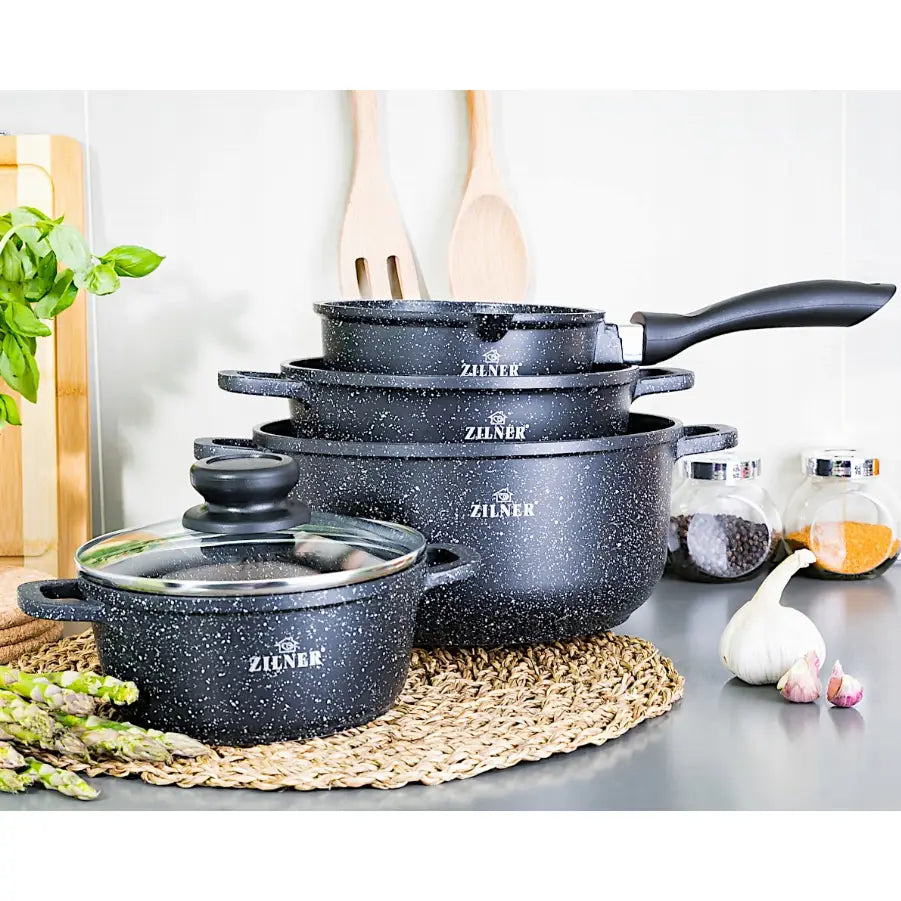 Komplett sett med sorte, marmorbelagte gryter og stekepanne med hvite prikker, stablet fra siden.