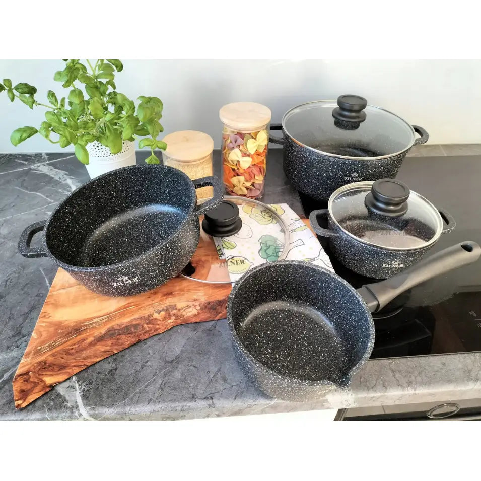 Komplett grytesett med marmorbelegg, sett ovenfra med glasslokk, urter og skjærebrett på kjøkkenbenk.