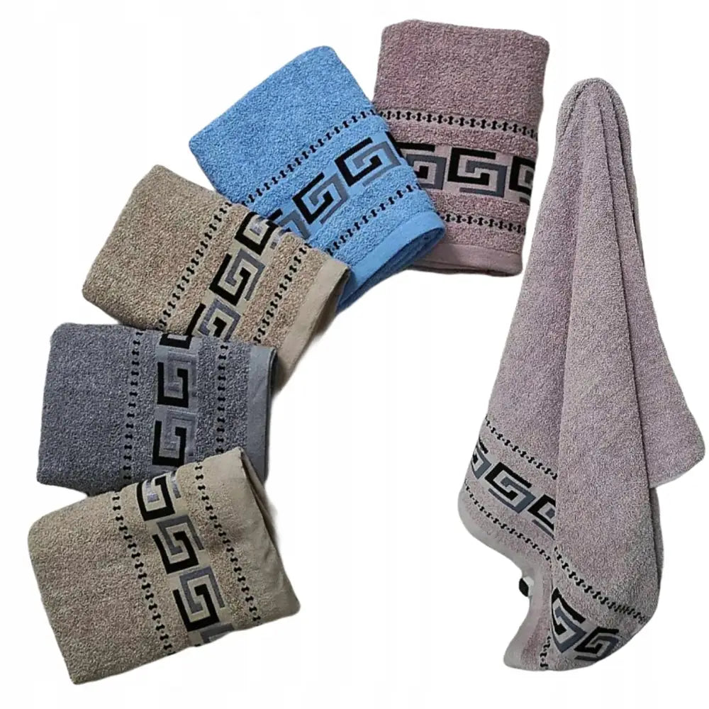 Komplett sett badehåndklær i fem farger, liggende og ett opphengt, med svart og hvitt kantmønster.