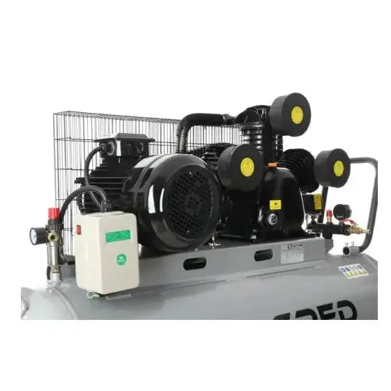 Kompressor med tre stempler, svart og grå, skrått fotografert med synlige ledninger, gule detaljer og metallgitter.