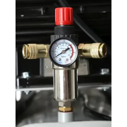 Kompressorens trykkmåler med rund hvit skive, messingkoblinger og rød justeringsknott sett forfra.