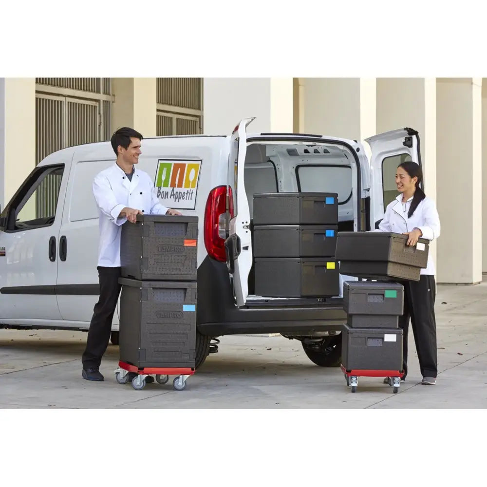 Kontainer termobox EPP CAMBRO for GN 1/1-container, flyttes på tralle av to kokker foran hvit varebil.